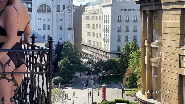 A woman undresses on a balcony in the city center. Public flashing.